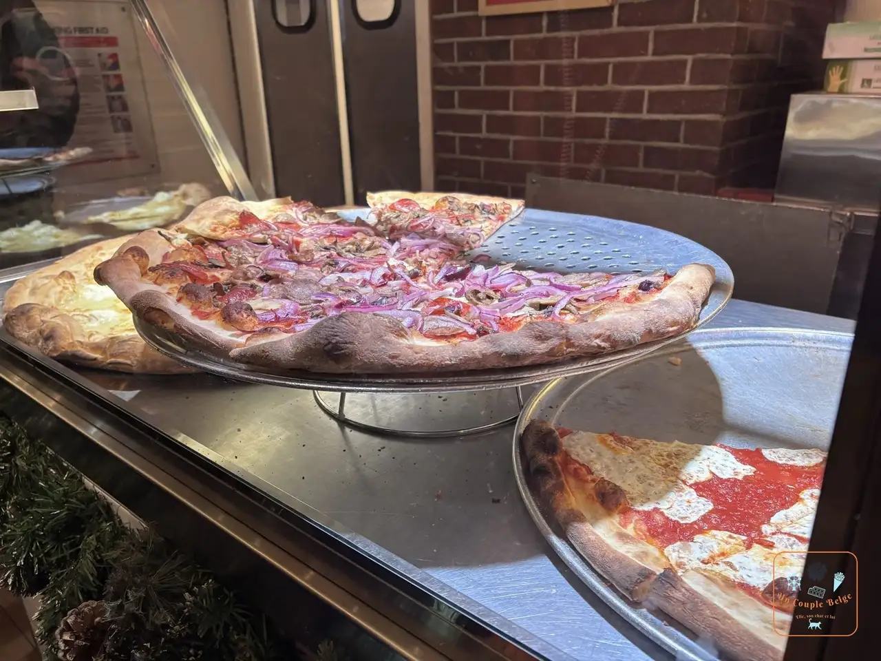 Pizza aux oignons rouges et pizza fromage dans la vitrine de Joe's Pizza